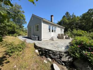 a small white house with a stone patio at Charming sea view in Bergen