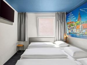 a room with four beds and a window at B&B HOTEL Flensburg-City in Flensburg