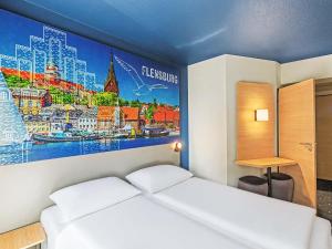 a bedroom with a white bed with a painting on the wall at B&B HOTEL Flensburg-City in Flensburg +20 photos