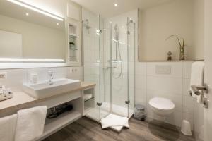 a white bathroom with a sink and a shower at Akzent Hotel Löwen in Langenargen +40 photos
