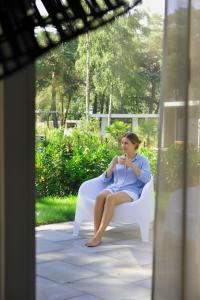 a woman sitting on a white chair on a porch at Luxe Boshuisje Lodge Wildblick, adults only Haarle, Sallandse Heuvelrug in Haarle