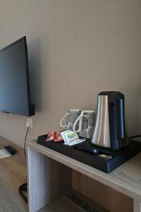 ein Schreibtisch mit Fernseher und Kaffeemaschine darauf in der Unterkunft Lignum Hotel in Miskolctapolca