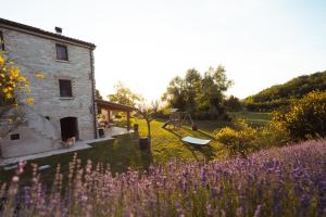 a house with a field of purple flowers next to a building at Tenuta del Picchio in Colombara