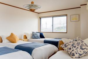 a room with three beds and a window at DAI HOSTEL Ayase in Fukaya
