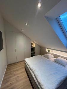 a bedroom with a large white bed with a window at Chambre haute in Eupen