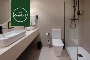 a bathroom with a toilet and a green sign at Sercotel Delfos Andorra in Andorra la Vella
