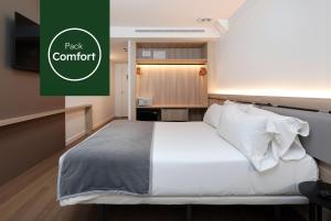 a bedroom with a white bed and a green sign that reads pack comfort at Sercotel Delfos Andorra in Andorra la Vella