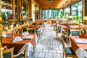 a restaurant with tables and chairs and windows at Hotel Restaurant - Häuserl im Wald Graz in Graz