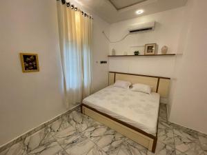 a small bed in a room with a marble floor at Pristine Apartment in Gwagalada