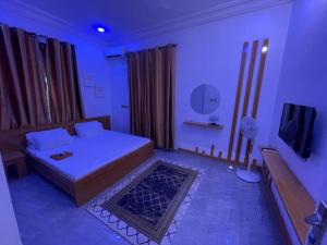 a room with a bed and a tv in it at Pristine Apartment in Gwagalada