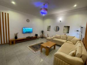 a living room with two couches and a tv at Pristine Apartment in Gwagalada