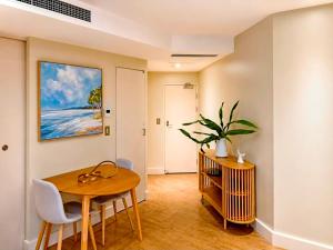 a dining room with a table and chairs and a painting at Bugalmaa - Cotton Beach in Casuarina