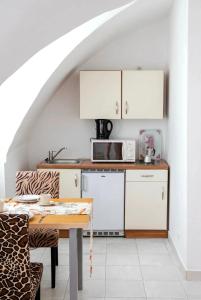 a kitchen with white cabinets and a table at Historic Flat & Private Courtyard in Bruck an der Leitha +7 photos