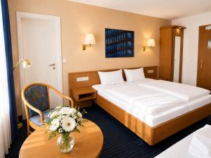 una camera d'albergo con un letto e un tavolo con fiori di Mirage City Hotel Stuttgart Zentrum a Stoccarda Altre 62 foto