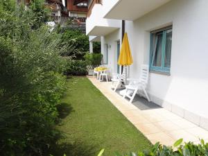 a patio with two chairs and a table and an umbrella at Renates Ferienwohnungen in Meltina +6 photos