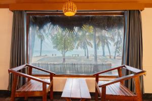 a table with two benches in front of a window at Sea Shells Beach Resort Agatti in Agatti