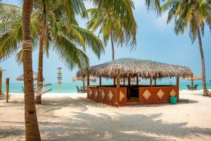 a hut on a beach with palm trees and the ocean at Sea Shells Beach Resort Agatti in Agatti
