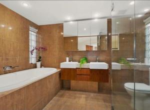 a bathroom with a tub and two sinks and a toilet at Bugalmaa - Cotton Beach in Casuarina +12 photos