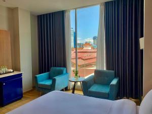 a hotel room with two chairs and a large window at Ngan Ha Hotel - Ben Thanh Central in Ho Chi Minh City +40 photos