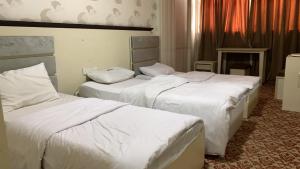 two beds in a hotel room with white sheets at Chwar chra hotel in Erbil