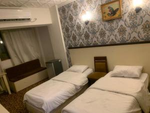 a room with three beds and a wall with a wallpaper at Chwar chra hotel in Erbil