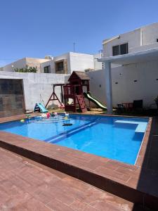 a large blue swimming pool with a playground at Casa completa, 4 dormitorios, 7 camas dobles, 4 sofá cama, 3 baños 1 en planta baja, cocina equipada, consola Arcade, asador, juguetes para niños, plancha, secadora, cafetera, etc, fraccionamiento privado, zona de vías rápidas y toallas in Torreón