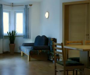 a living room with a blue couch and a table at Renates Ferienwohnungen in Meltina