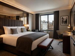 a hotel room with a bed and a desk and a window at Metropole Hotel in London