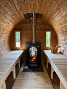 a fireplace in a log cabin with two benches at Villa Vera - Comfort, Space, Sauna & Hot Tub in Private Garden in Zeewolde