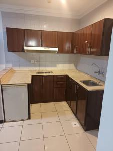 an empty kitchen with wooden cabinets and a sink at Jumeirah in Jeddah