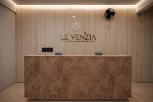 a reception desk in a lobby with a sign on a wall at Le Venzia in Sultan Bathery