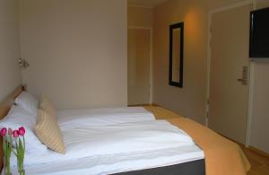 uma cama com lençóis brancos e almofadas num quarto em Heimat Brokelandsheia em Gjerstad