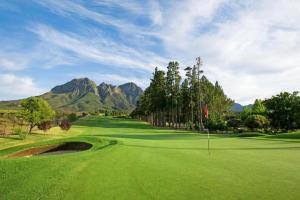 a green golf course with mountains in the background at Summer Set West in Somerset West