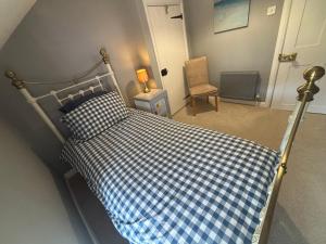 a bedroom with a bed with a blue and white checkered bedspread at Cotford Cottage in Sidmouth +16 photos