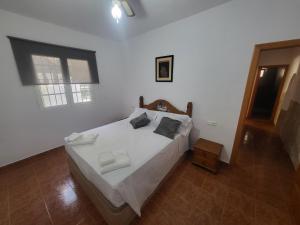 a bedroom with a bed with white sheets and a window at La Casita del Mar in Torrox