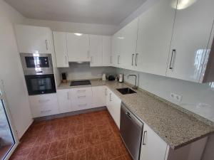 a white kitchen with white cabinets and a sink at La Casita del Mar in Torrox