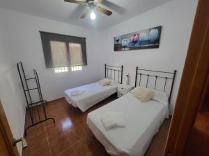 a bedroom with two beds and a ceiling fan at La Casita del Mar in Torrox +6 photos