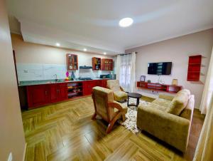 a living room with two couches and a kitchen at Kijani Pazuri Cottages in Lushoto