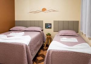 two beds sitting next to each other in a bedroom at Sol do Jalapão Kitnets Completas com Ar a 6km do Aeroporto de Palmas in Palmas