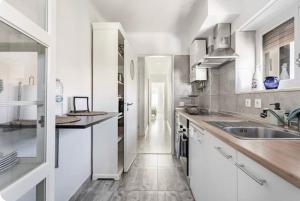 a kitchen with white cabinets and a sink at Casa da Matilde in Estoril