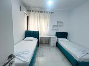 two beds in a small room with a desk and a bed sidx sidx at Twobedrooms house in Polisi i Vogël