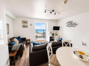 a living room with a couch and a table at Dog friendly sea front apartment with balcony in Pendine
