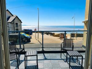 a balcony with chairs and a view of the beach at Dog friendly sea front apartment with balcony in Pendine
