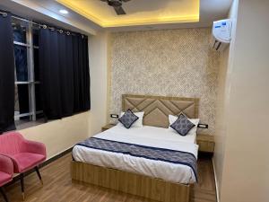a bedroom with a bed and a pink chair at Hotel Keshav Villa in Mandhana