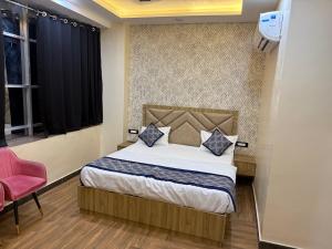 a bedroom with a bed and a pink chair at Hotel Keshav Villa in Mandhana