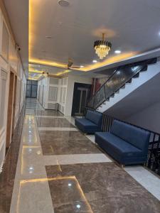 a hallway with blue couches and a staircase in a building at Hotel Keshav Villa in Mandhana