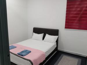 a small bedroom with a white bed with a red window at Kenari homestay in Gopeng +5 photos