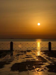 a sunset on the beach with the sun setting over the water at Spina home in Vieste +3 photos