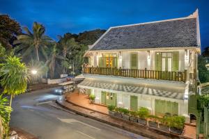 a large white house with a balcony on a street at Nava Luang Prabang Hotel in Luang Prabang