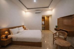 a bedroom with a bed and a table and a chair at AA Guest House Padonan in Dalung